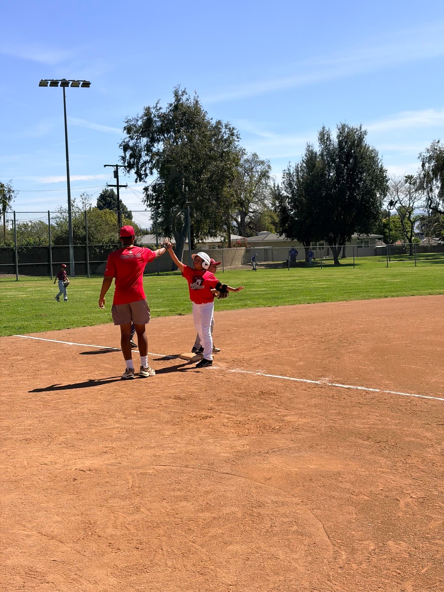 Player high-fiving coach at first base